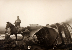 German troops riding past a destroyed vehicle, date and location unknown