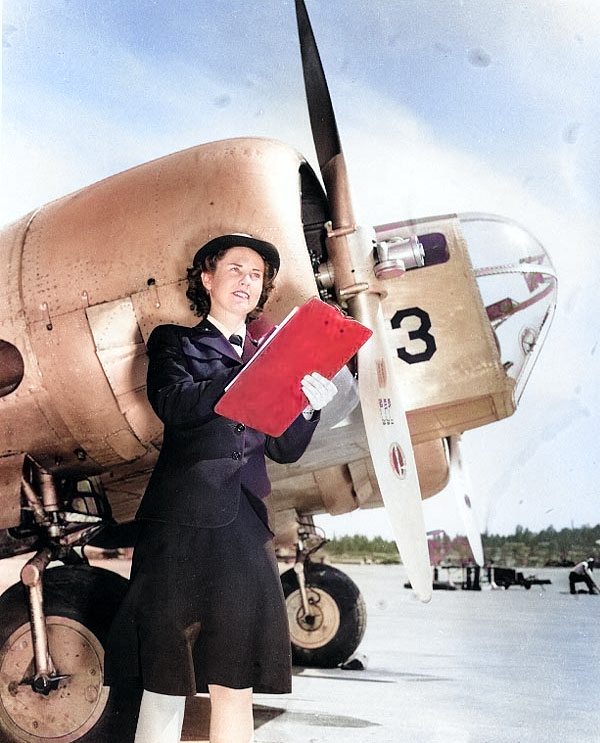 WAVES personnel Bernice Garrott marking off an aircraft check-off list, Naval Air Station, Seattle, Washington, United States, 7 Jul 1943; note SNB-1 training aircraft [Colorized by WW2DB]