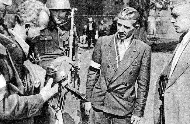 Polish resistance fighter Captain Cyprian Odorkiewicz inspecting a captured German Army cap held by Wacław Jastrzębowski, Okólnik gardens, Warsaw, Poland, 14 Aug 1944; note captured MP 40 submachine gun