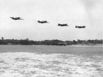 P-51A Mustangs do a low pass over a forward air field of the 1st Air Commandos, Burma, Apr 1944. Note also a B-25H Mitchell and an L-1 Vigilant