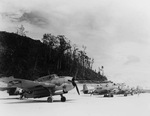 Marine TBM-1C Avengers lined up along the airstrip at Munda, New Georgia, Solomon Islands in late 1943. Note open bomb bays, improvised wheel chocks, flame dampener on the exhaust port of the nearest plane, and different versions of the National Insignia
