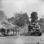 M3 Lee tank passing a burning building in a Burmese village south of Mandalay, Burma, 20 Mar 1945.