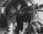 Staff Sergeant Maynard Smith at a machine gun in a B-17 bomber, mid-1943