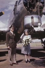 The United Kingdom’s Princess Elizabeth of York holding onto her hat against the wind at RAF Thurleigh, Bedfordshire, England, 6 Jul 1944. She is standing with Col. George Robinson, base commanding officer.