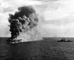 Escort carrier USS Ommaney Bay on fire after being struck by a Japanese special attack aircraft in the Sulu Sea, Philippines, 4 Jan 1945. The destroyer USS Patterson can be seen approaching to help.