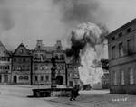 Men of US 101st Infantry Regiment running past a burning fuel trailer in square of Kronach, Bayreuth, Germany, 14 Apr 1945