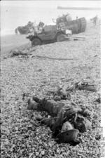 Remains of a Canadian soldier on the beach after the failed raid on Dieppe, France, Aug 1942; note Daimler Scout Car and Churchill tank in background