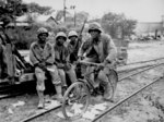 African-American men of the US Marine Corps Third Ammunitions Company at Saipan, Mariana Islands, Jun 1944; Pfc Boykin on bicycle; Pfcs Anthony, Shackelford, and Purdy watching