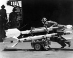 A crewman of USS Hancock preparing Sidewinder missiles, off Vietnam, Apr 1967