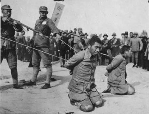 Chinese soldiers executing two Chinese men who had been found guilty of collaboration with the Japanese, China, circa late 1930s
