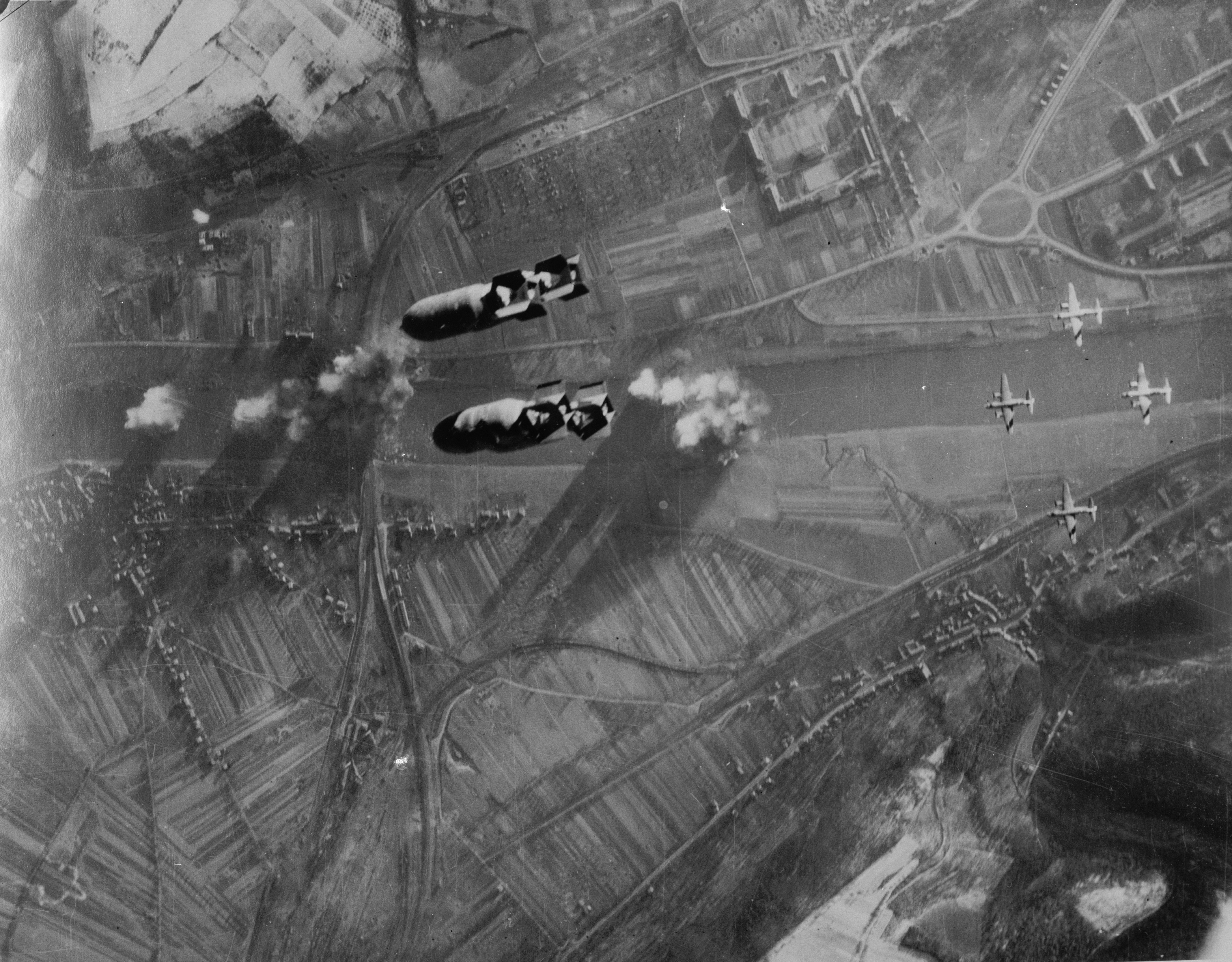 Bomb bay view of Martin B-26 Marauder bombers of the 323rd and 394th Bomb Groups drop 122 tons of bombs in an effort to take down the railroad bridge across the Moselle river at Trier, Germany, 24 Dec 1944.