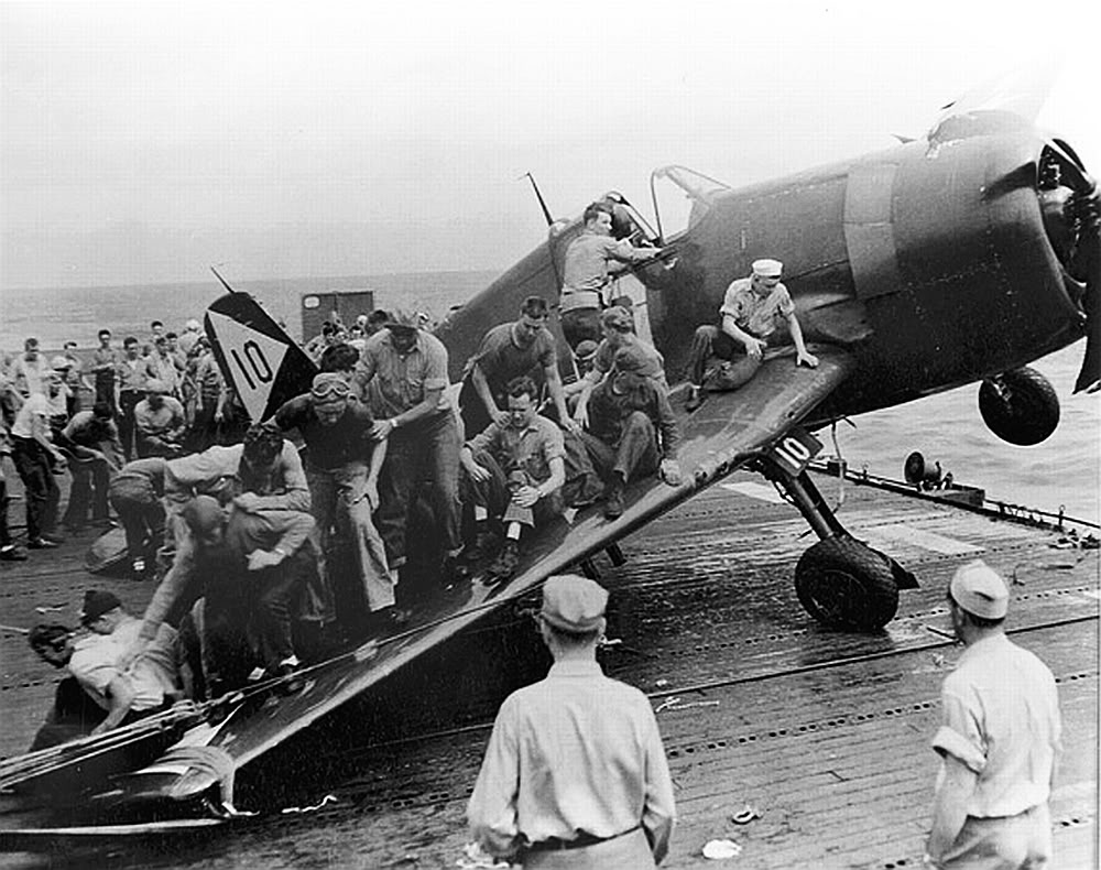 Carrier Monterey Crewmen act as a counter-weight on the starboard wing of an F6F-5 Hellcat to keep the aircraft from tumbling over the edge of the flight deck, 1945.