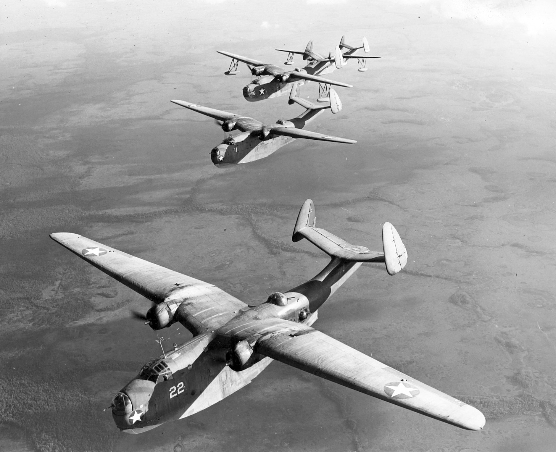 Two PBM-1 (front) and two PBM-3 (back) in flight, 1942. The PBM-1s are from an early production series with retractable floats that were discontinued for principal production. Location unknown. Photo 2 of 2
