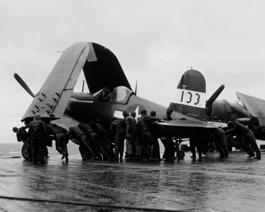 F4U-1D Corsair with Marine Squadron 216 aboard USS Wasp (Essex-class) being moved onto the deck-edge elevator on its way to the hangar deck following a strike against targets in and around Tokyo, Japan, Feb 17, 1945.