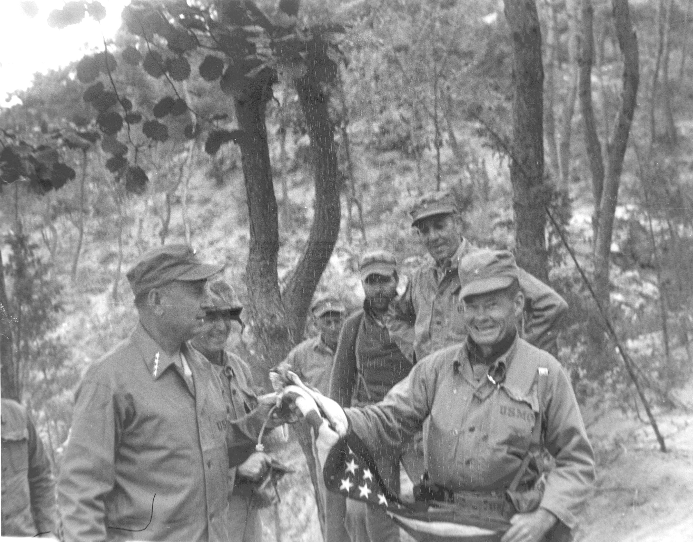 Marine Commandant Clifton Cates (left) receives the first flag flown over the recaptured Seoul, South Korea from 1st Marine Commander Col Chesty Puller, Oct 3 1950.
