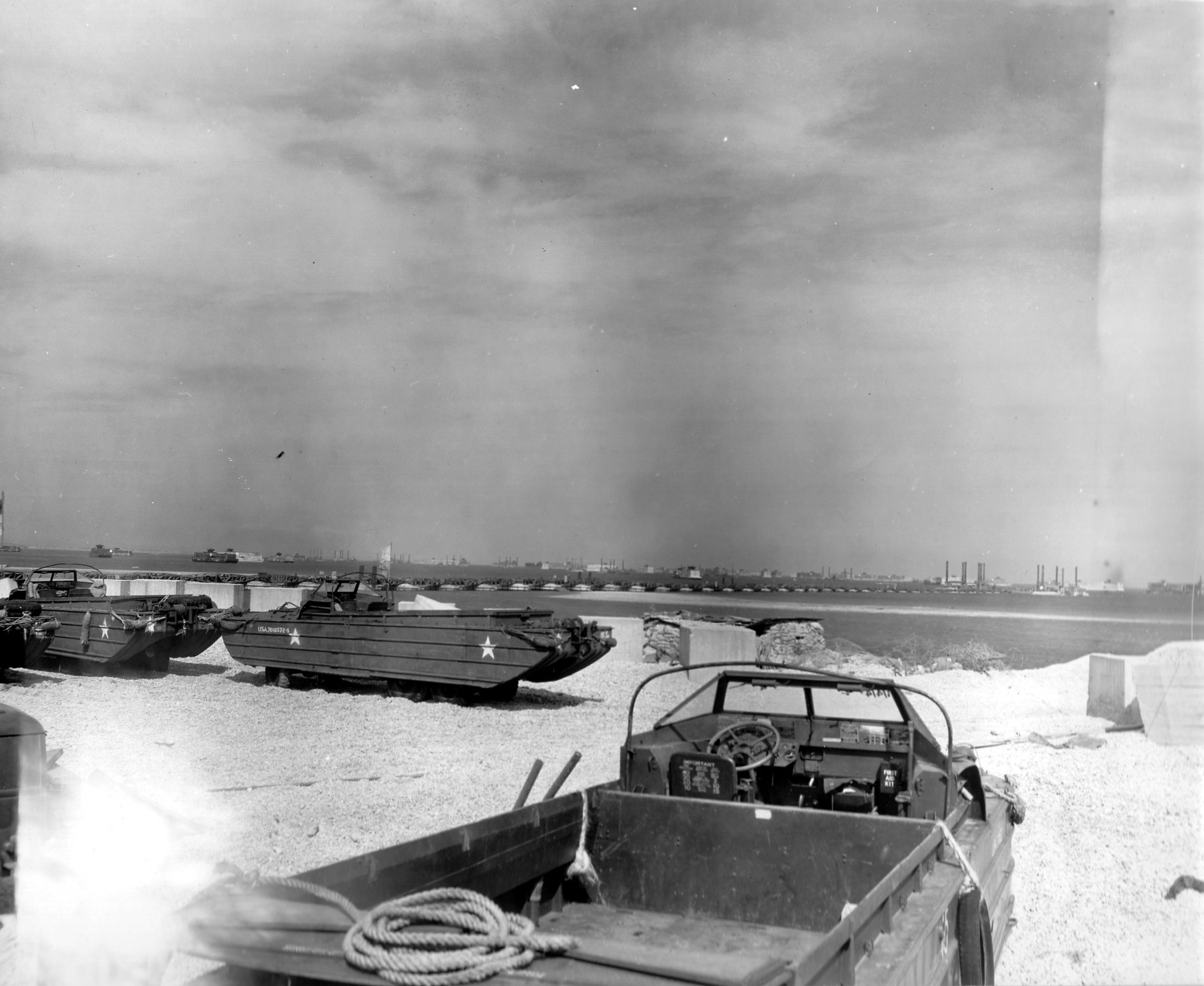 DUKWs on the beach at Selsey, West Sussex, England prior to the Normandy invasion, May 1944. Note components of the artificial Mulberry Harbors in the background awaiting deployment.