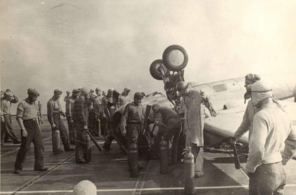 Fire control crews responded to an FM-2 Wildcat that had nosed all the way over on landing aboard training aircraft carrier USS Sable on Lake Michigan, United States, 1944.