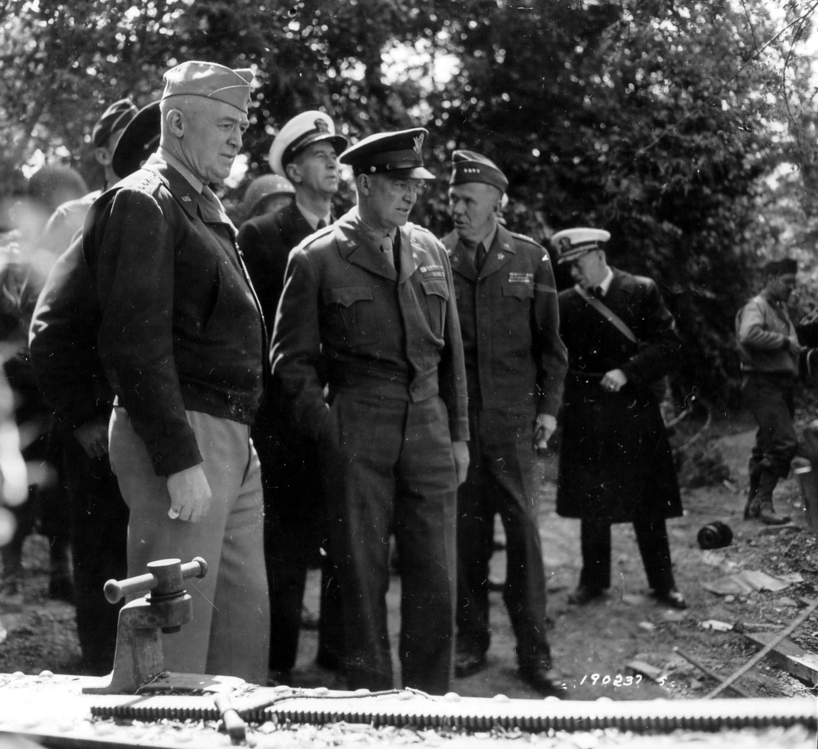 Gen “Hap” Arnold, Gen Dwight Eisenhower, Adm Ernest King (white cap behind Eisenhower), and Gen George Marshall visit the guns moved from Pointe du Hoc, Normandy, France, Jun 12, 1944.