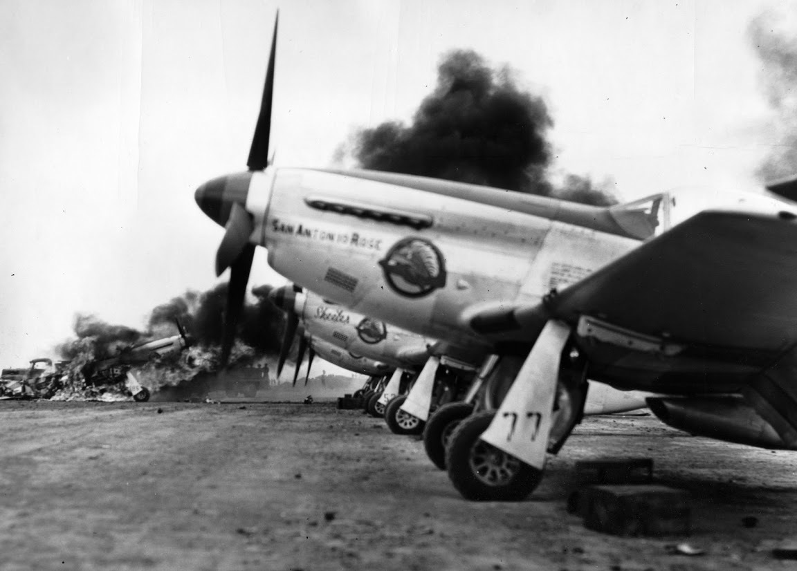P-51 Mustangs of the 45th Fighter Squadron lined up on South Field, Iwo Jima, Mar 7, 1945. Fire is from a P-51 from the 78th Fighter Squadron that crashed on landing and struck two parked 45th Fighter Squadron P-51s.