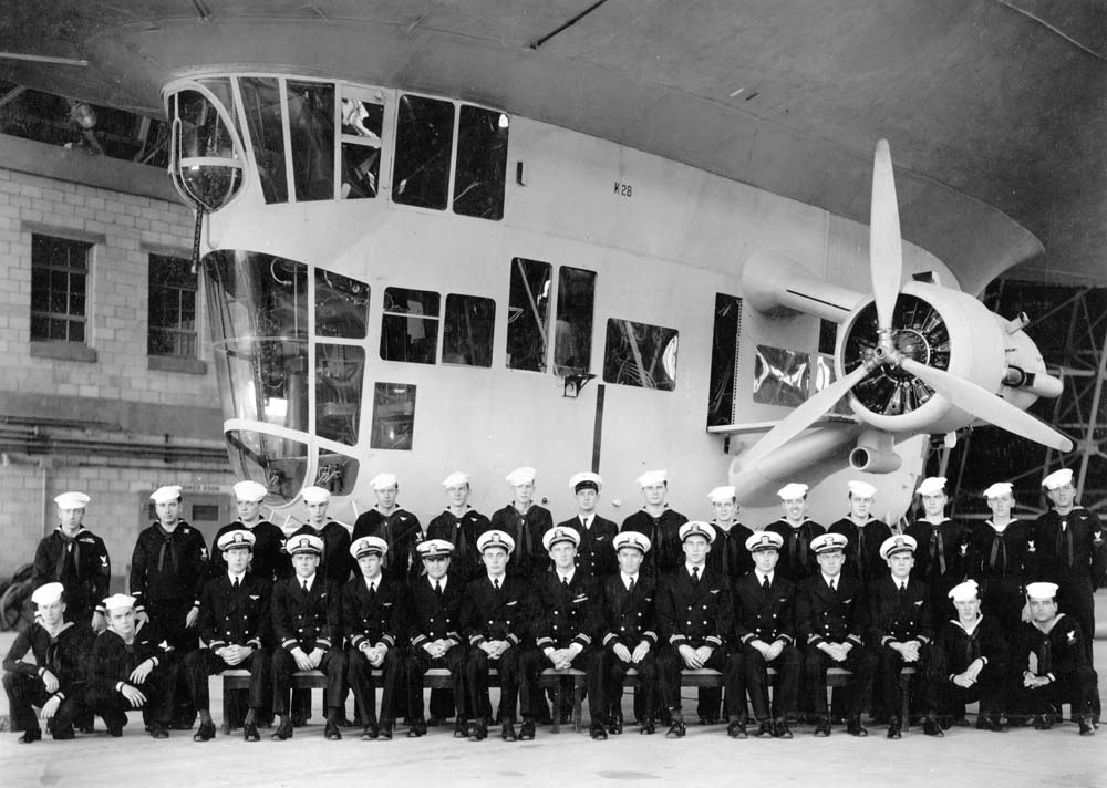 Detachment One of US Navy Lighter Than Air Utility Squadron ZJ-1 sit for a group photograph in front of airship K-28 control car, Meacham Field, Key West, Florida, United States, June 1, 1945.