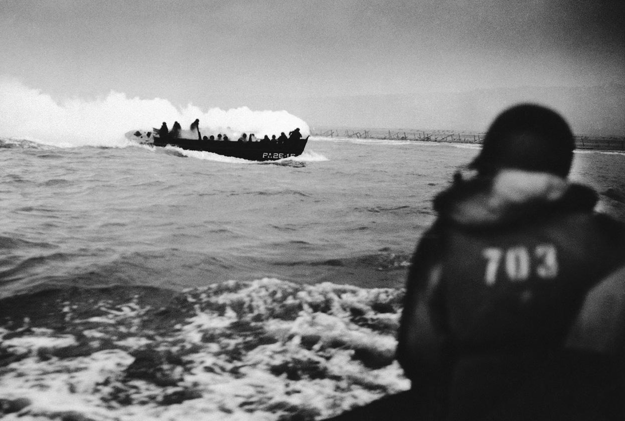 LCVP landing craft from Amphibious Transport Ship USS Samuel Chase approaching Omaha Beach. The boat is smoking from a fire that resulted when a German machine gun bullet hit a soldier’s hand grenade.