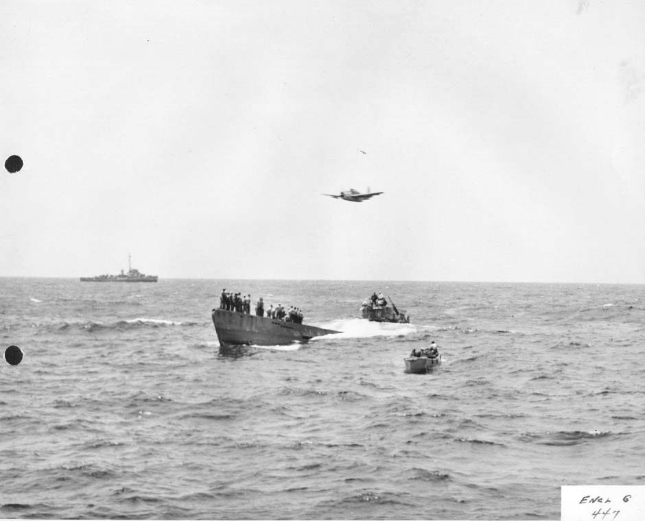 TBF Avenger from Escort Carrier USS Guadalcanal overflying the captured German Type IXC submarine U-505 as a salvage crew assembles on the U-Boat’s bow. A US whale boat and an escort stand by, 7 Jun 1944.