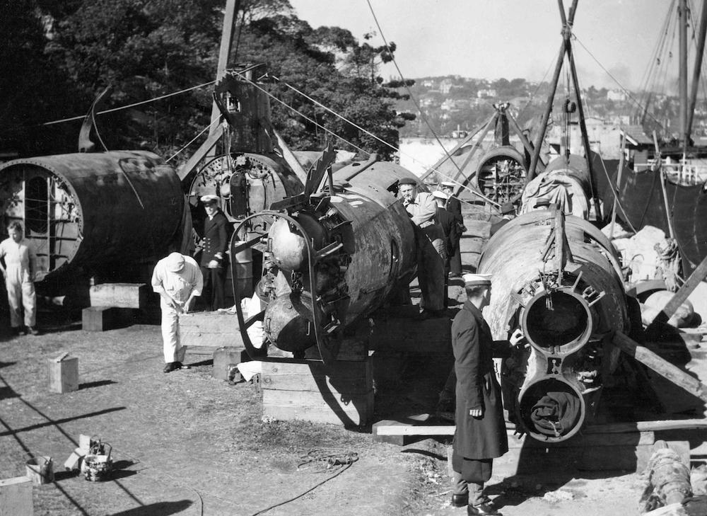 Royal Australian Navy personnel examining the hulls and pieces of the Japanese Type A midget submarines recovered from Sydney Harbor after the 31 May 1942 raid.