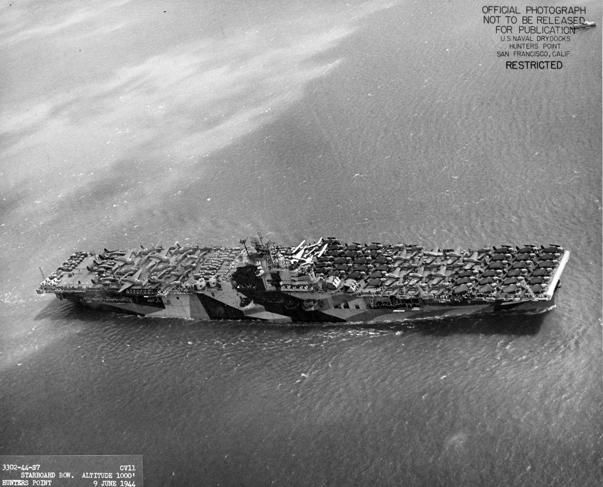 USS Intrepid departing San Francisco, California, 9 Jun 1944 packed with vehicles, equipment, and aircraft including SBD Dauntless, F6F Hellcats, C-45 Expeditors, PV-1 Venturas, and P-61 Black Widows. Photo 1 of 3