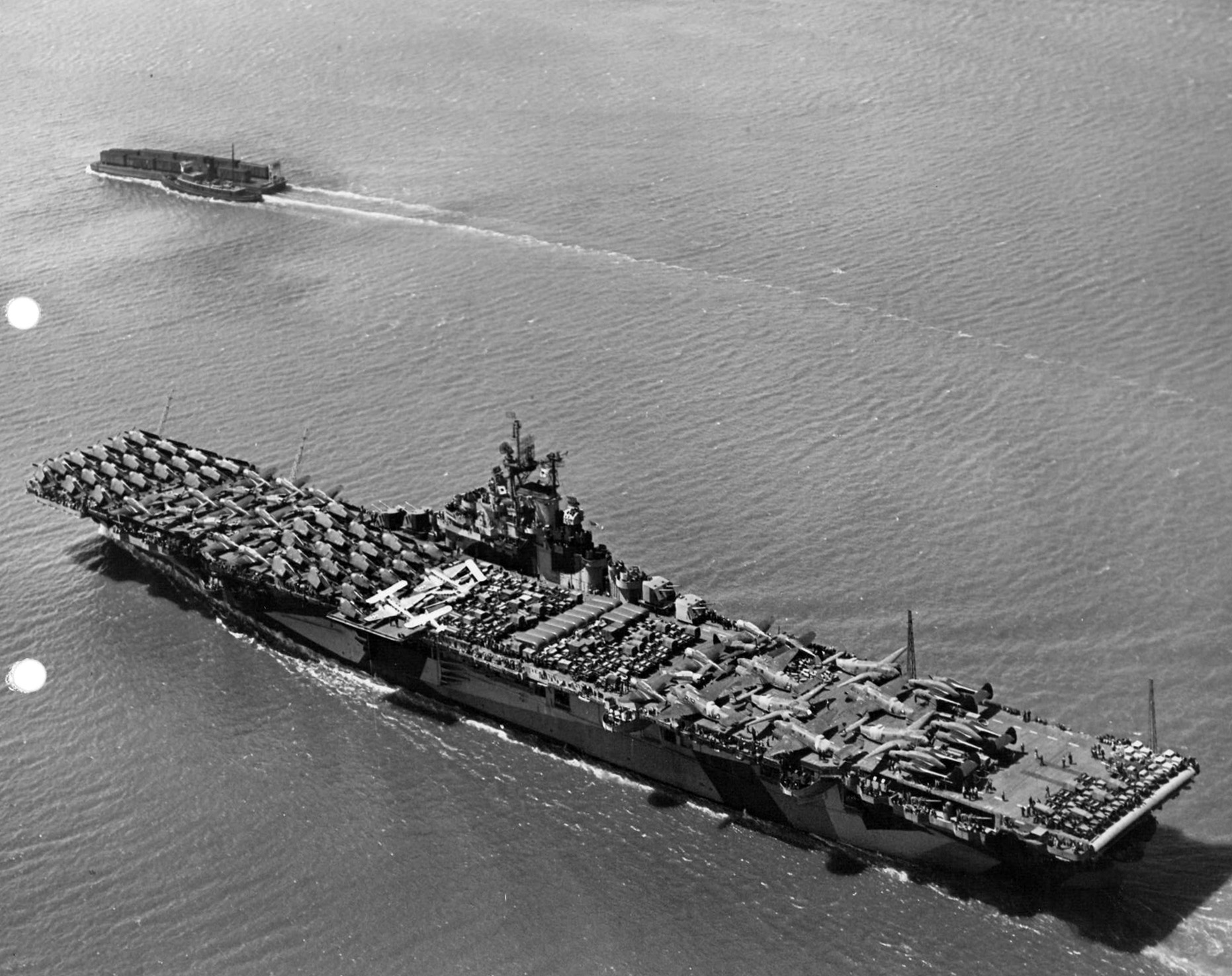 USS Intrepid departing San Francisco, California, 9 Jun 1944 packed with vehicles, equipment, and aircraft including SBD Dauntless, F6F Hellcats, C-45 Expeditors, PV-1 Venturas, and P-61 Black Widows. Photo 2 of 3