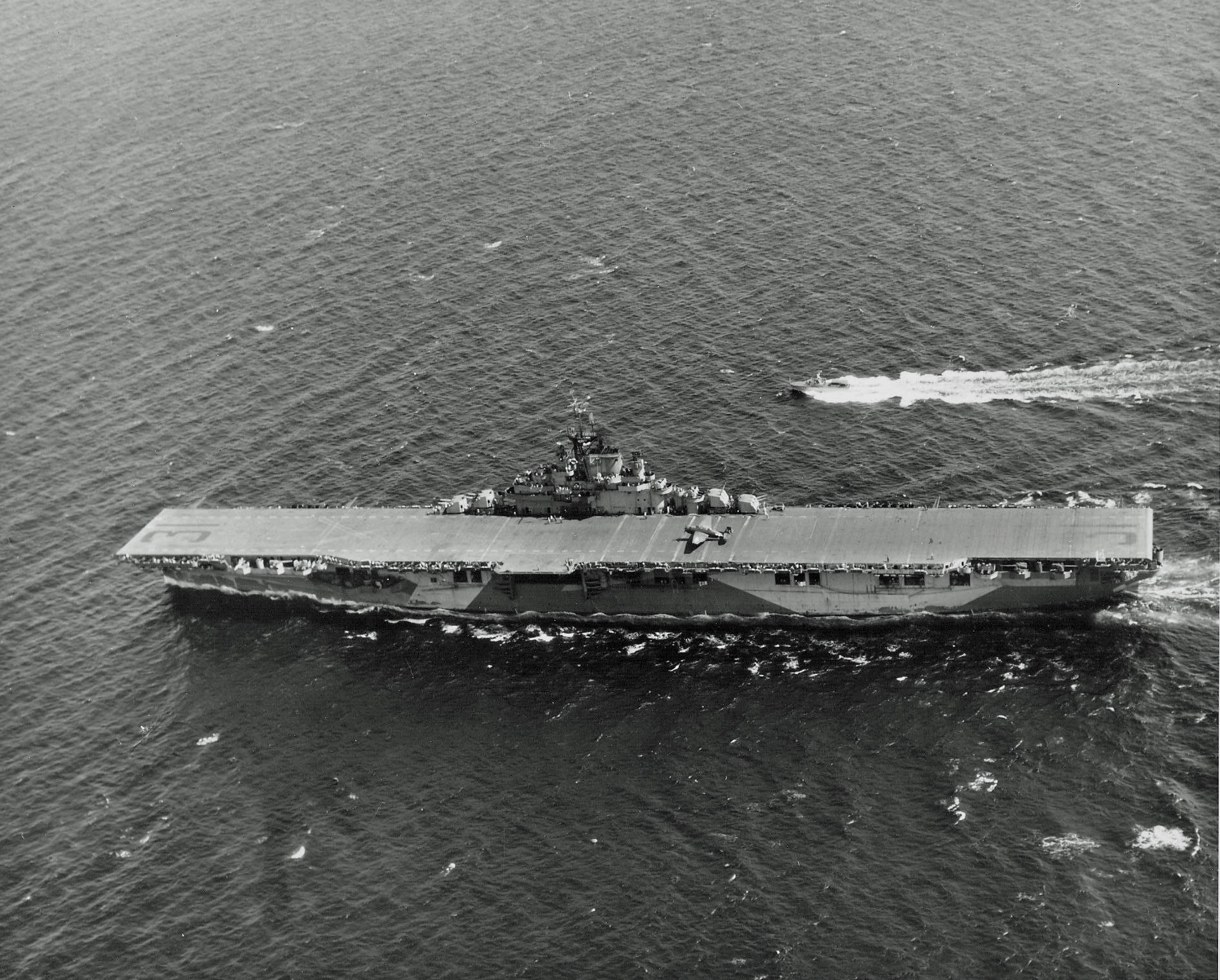 Essex-class carrier USS Bon Homme Richard cruising in the Gulf of Paria between Trinidad and Venezuela on her shakedown cruise, 7 Feb 1945. Note TBM Avenger on her deck and Coast Guard guard boat alongside