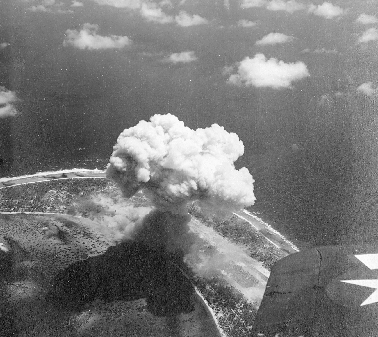 Strike photo of Kwajalein, Marshall Islands taken by aircraft from USS Enterprise, 30 Jan 1944. Note the rising mushroom cloud from the exploding Japanese ammunition dump.