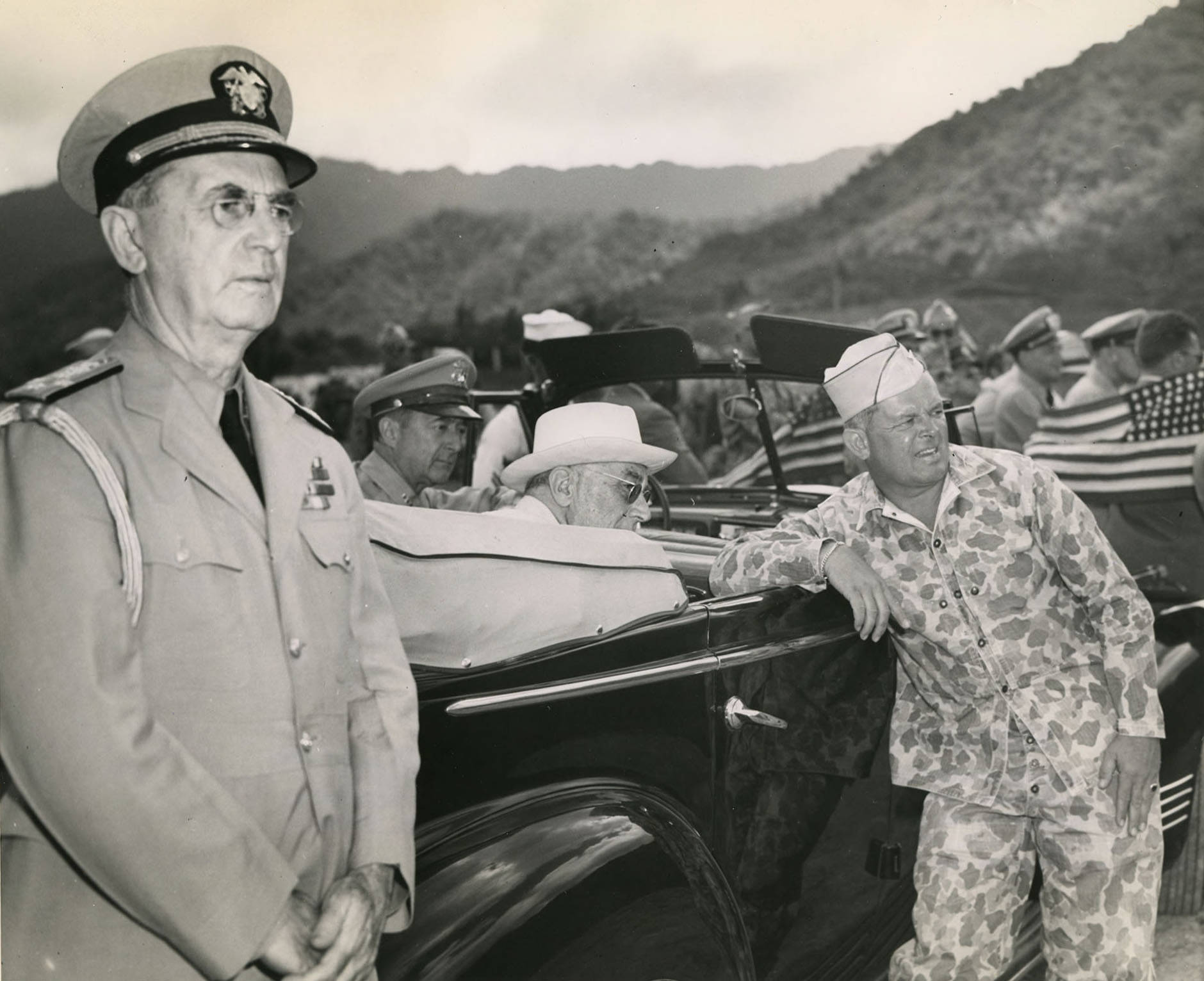 While touring Oahu, US Territory of Hawaii, President Franklin Roosevelt (seated in car) listened to Col William Saffarans (in jungle suit) at the Army’s Jungle Training Unit at Kahana Bay, 28 July 1944.