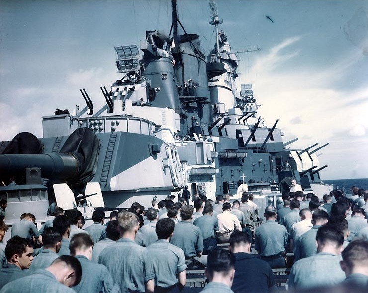 A Roman Catholic chaplain performing mass on the deck of USS Iowa as they closed on the Mariana Islands, Jun 1944. Note the colors of the ship’s paint and the 40mm and 20mm anti-aircraft mounts.