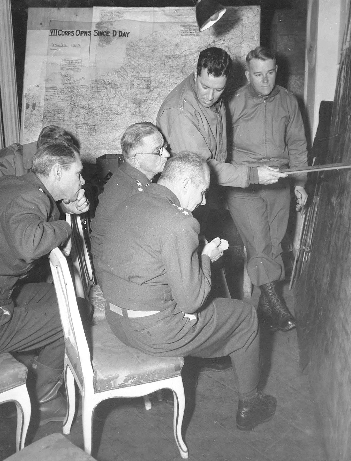 MGen ER “Pete” Quaseda, with pointer, conducting an Air-Ground Liaison briefing for LtGen Carl Spaatz (glasses) and LtGen James Doolittle (seated), VII Corps Headquarters, Münsterbusch, Germany, 19 Nov 1944
