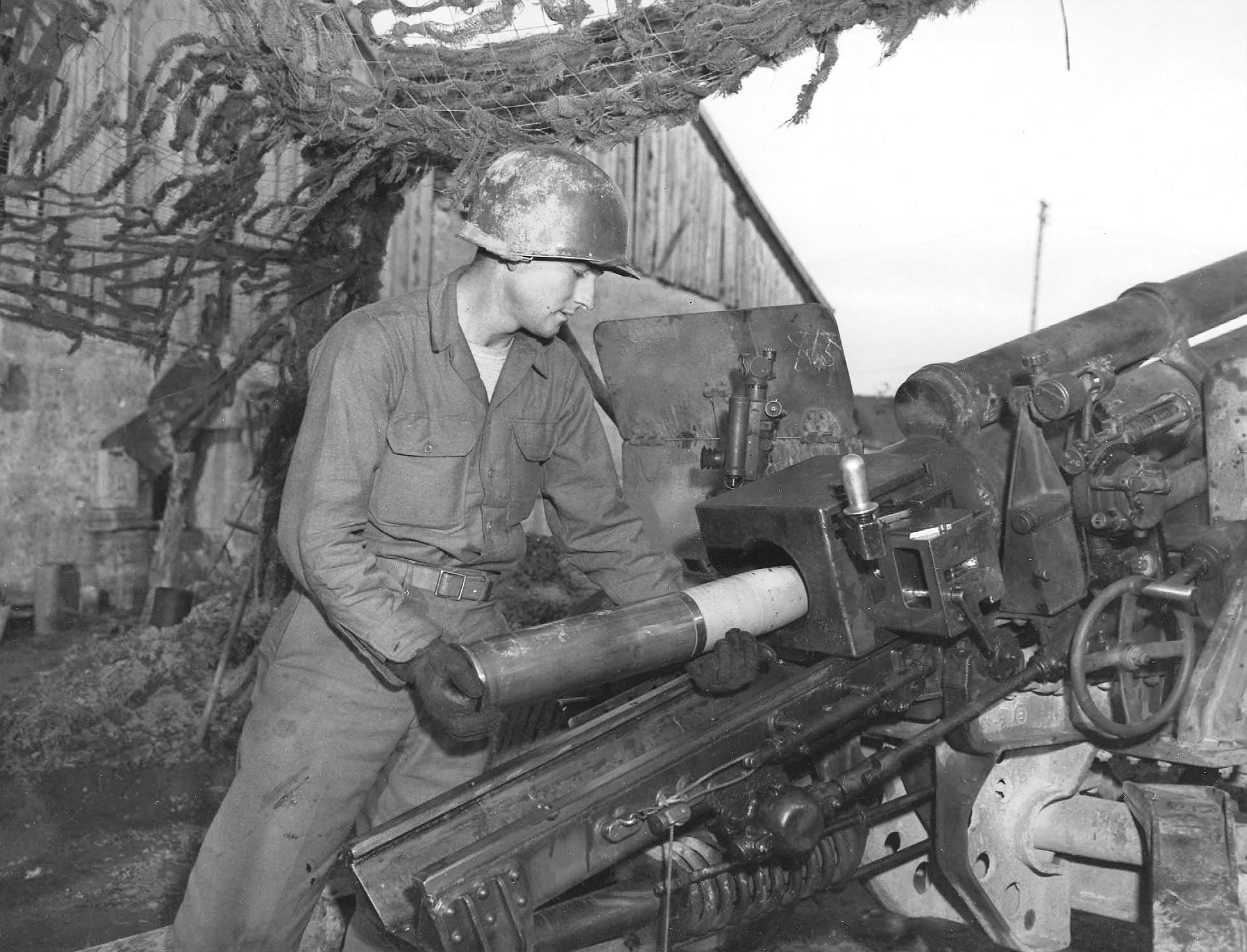 A member of the 131st Field Artillery Battalion loading a 105mm shell packed with D-ration chocolate bars for an infantry battalion cut off in the Belmont Sector, France, 29 Oct 1944