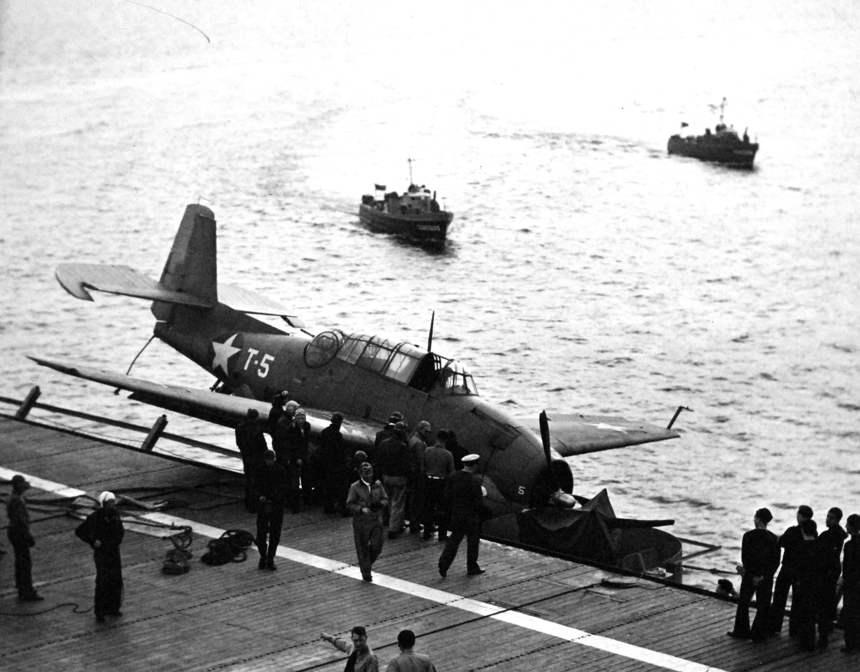 This TBF-1 Avenger attempted to land on the carrier USS Charger but missed the arresting wires and ended up tangled in the port catwalk, Chesapeake Bay, United States, 16 Mar 1943. Note US Coast Guard boats alongside.
