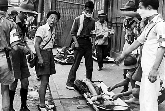 A boy scout tending to a toddler injured by Japanese bombing at South Station, Shanghai, China, 28 Aug 1937, photo 1 of 2