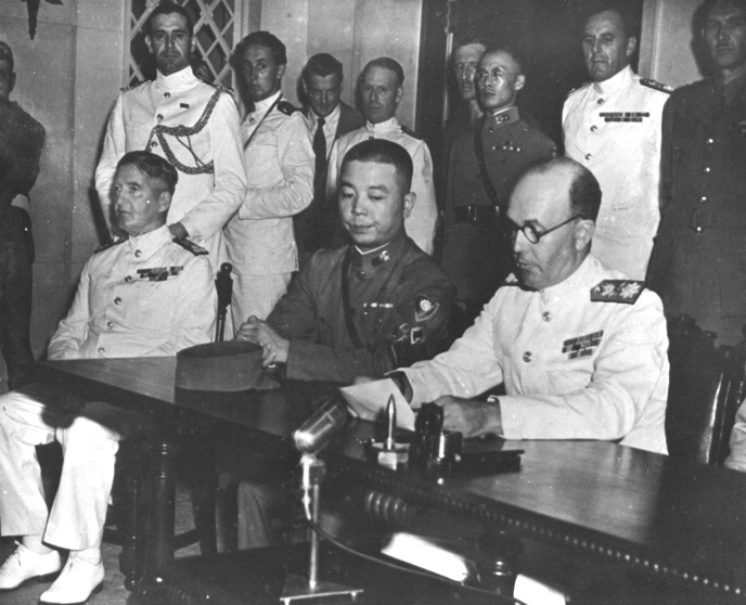 British Rear Admiral Cecil Harcourt reading the terms of surrender to the Japanese representatives, Government House, Hong Kong, 16 Sep 1945. At left is Chinese Major General Pan Hwa Kuei and far left is Adm Bruce Fraser