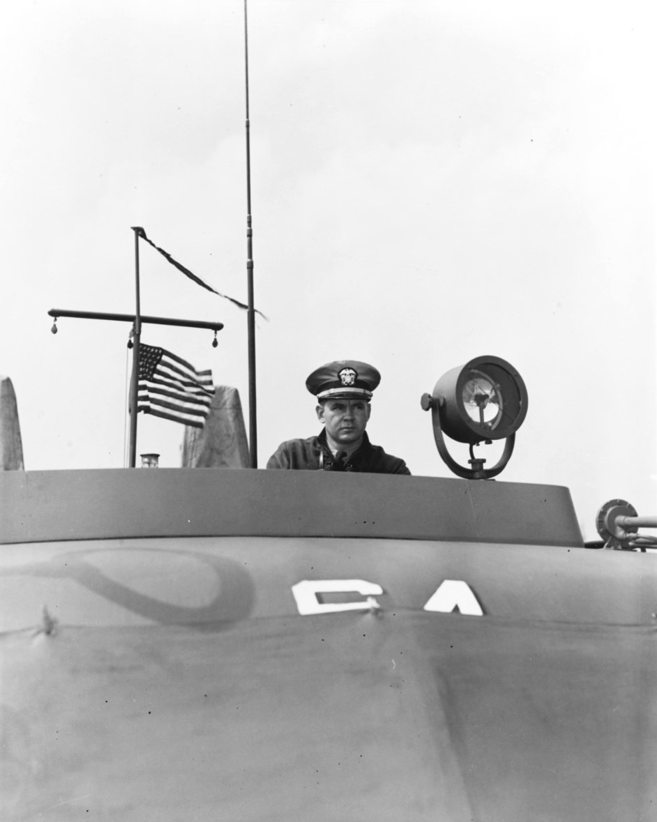 Lieutenant Commander John Bulkeley, United States Navy, at the helm of motor torpedo boat PT-64, a 77-foot Elco boat, Melville, Rhode Island, United States, circa 1942.