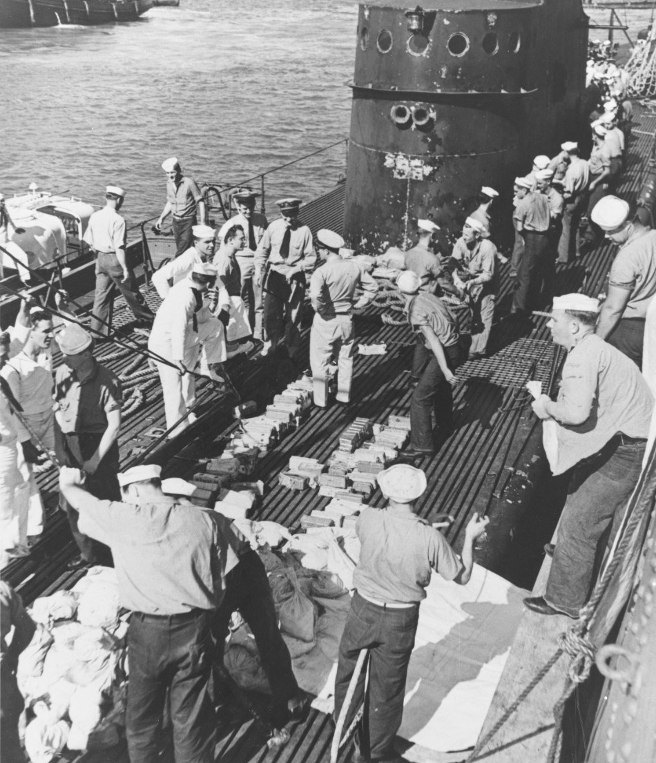 After arriving in Pearl Harbor, Hawaii in early Mar 1942, USS Trout crew members stacked 9 tons of gold bars and 13 tons of silver pesos evacuated from Corregidor, Philippines on the submarine’s deck for transfer to the USS Detroit.
