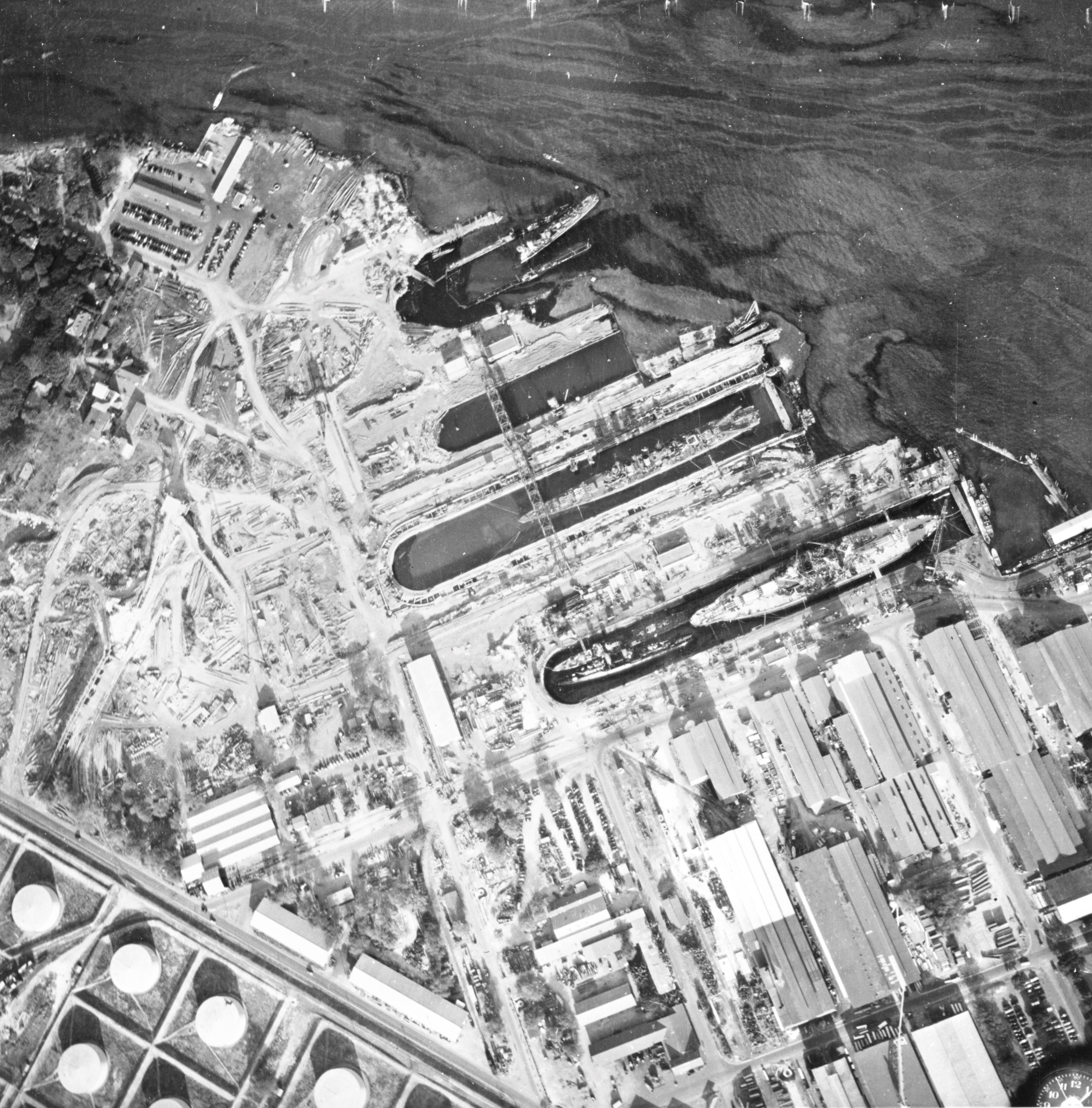 Aerial view of the drydocks at Pearl Harbor, Oahu, US Territory of Hawaii, 10 Dec 1941; note oil streaks. Pennsylvania is in Drydock #1 with Cassin and Downes and Helena is in Drydock #2. Photo 2 of 2.