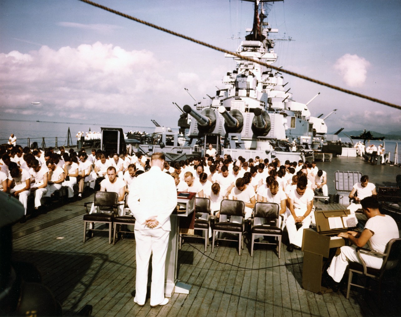 Navy Chaplain Lt Rival Hawkins conducting Sunday services on the USS Missouri’s fantail during the ship’s shakedown cruise in the Trinidad area, Aug 1944. The censored ship at right is the USS Alaska.