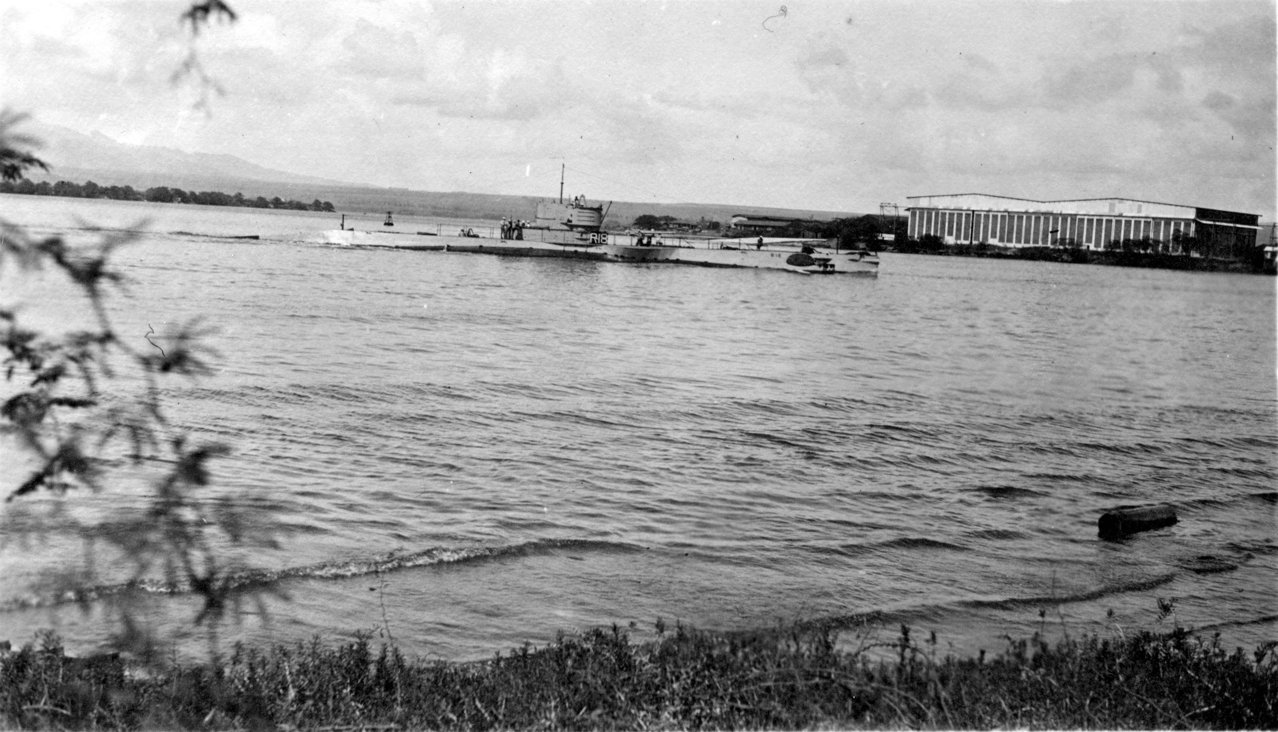 US Submarine R-18 rounding Hospital Point and entering Pearl Harbor’s Main Channel, Pearl Harbor, Hawaii, 1920s. Note Ford Island seaplane hangars on the right.