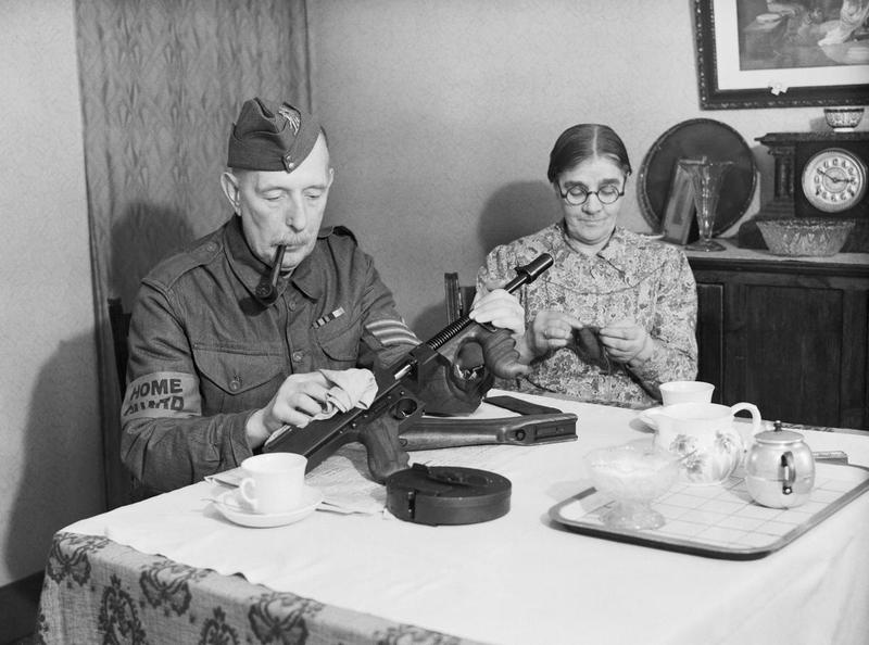 A sergeant in the Dorking Home Guard cleaning his Thompson submachine gun in his home, Dorking, southern England, United Kingdom, 1 Dec 1940
