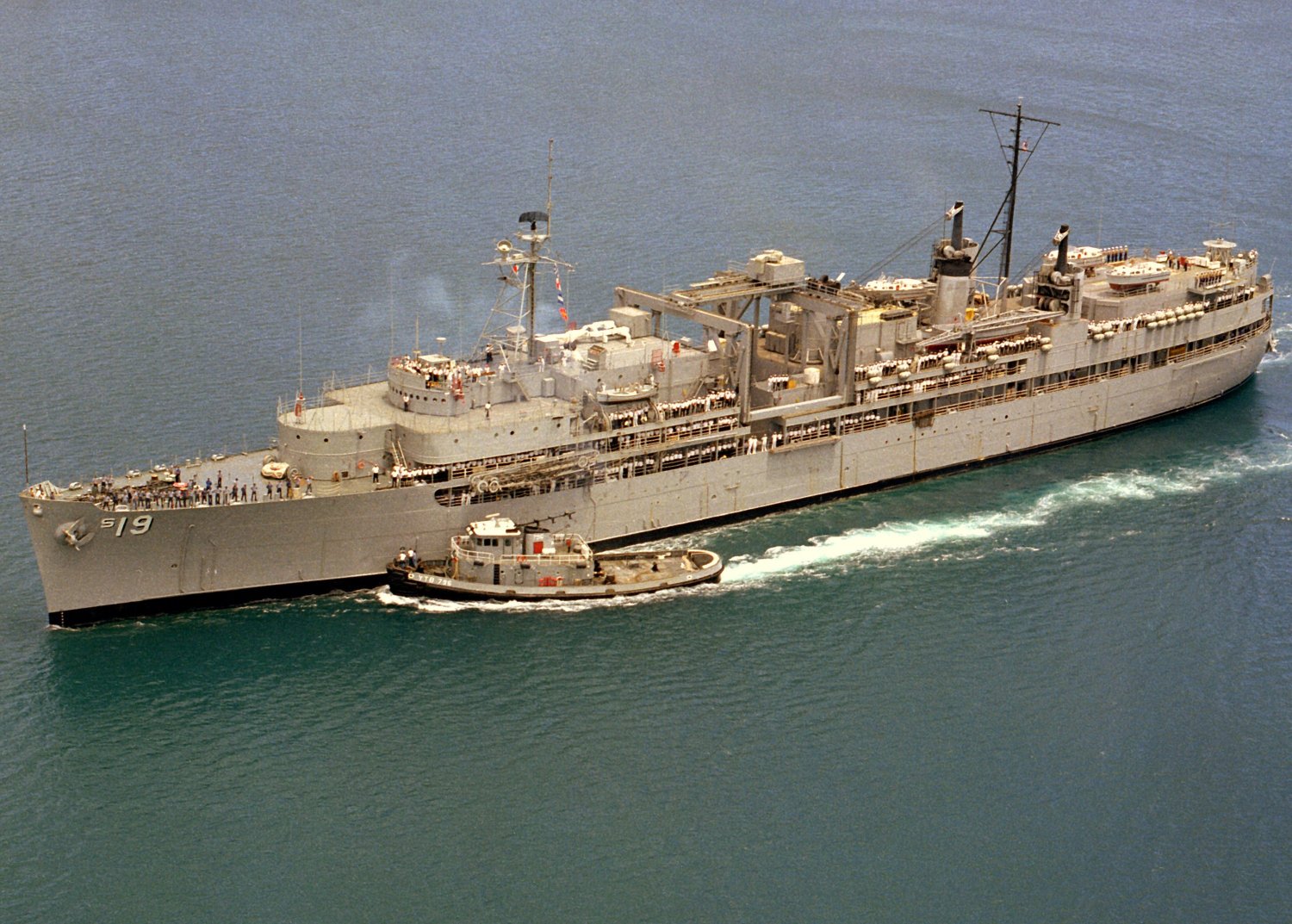 Tugboat Saco guiding USS Proteus into Naval Base Guam, 24 May 1980