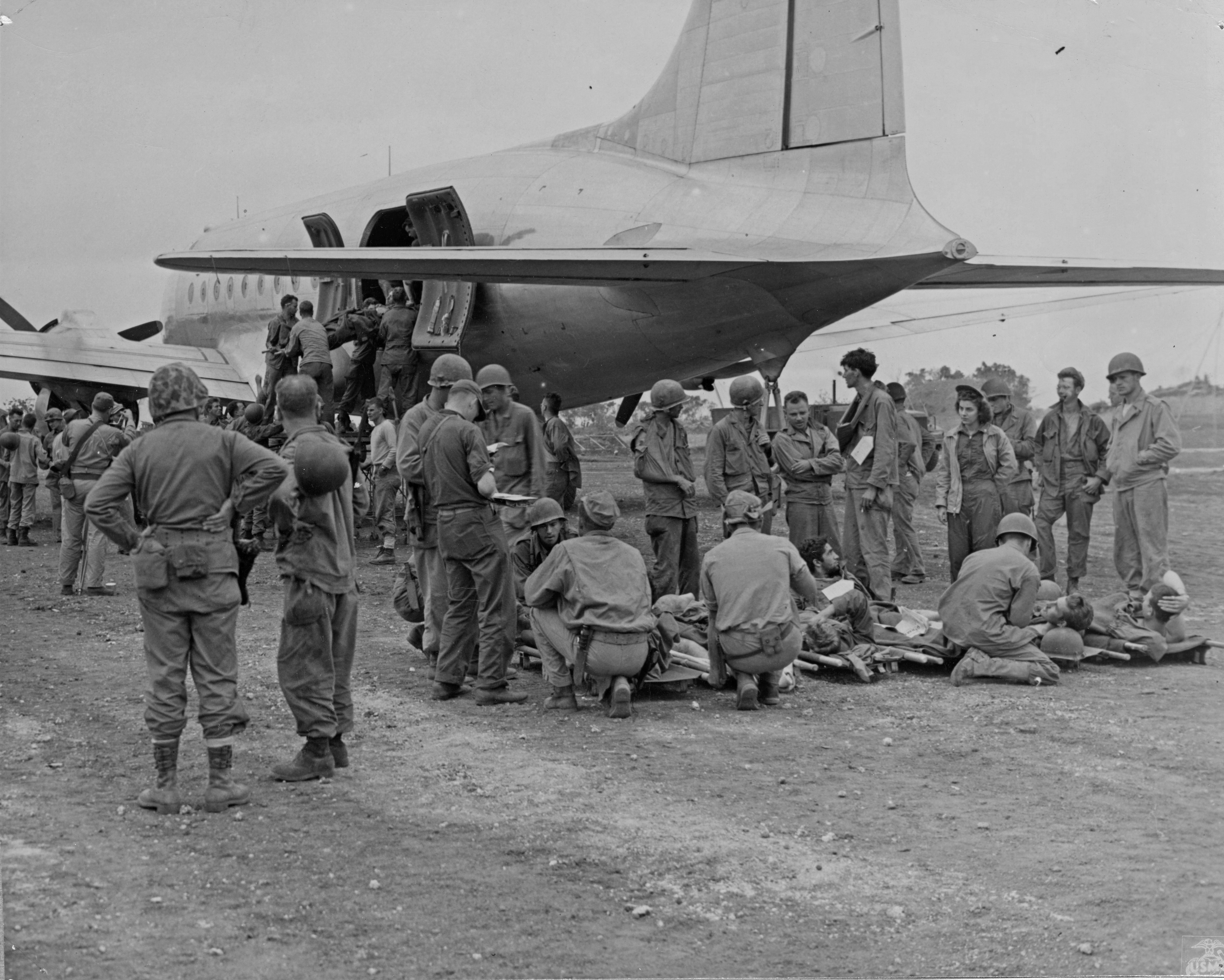 Wounded US Marines being loaded onto an aircraft for evacuation, Yontan Airfield, Okinawa, Japan, 1945; note female USN nurse Ensign Jane Kendeigh