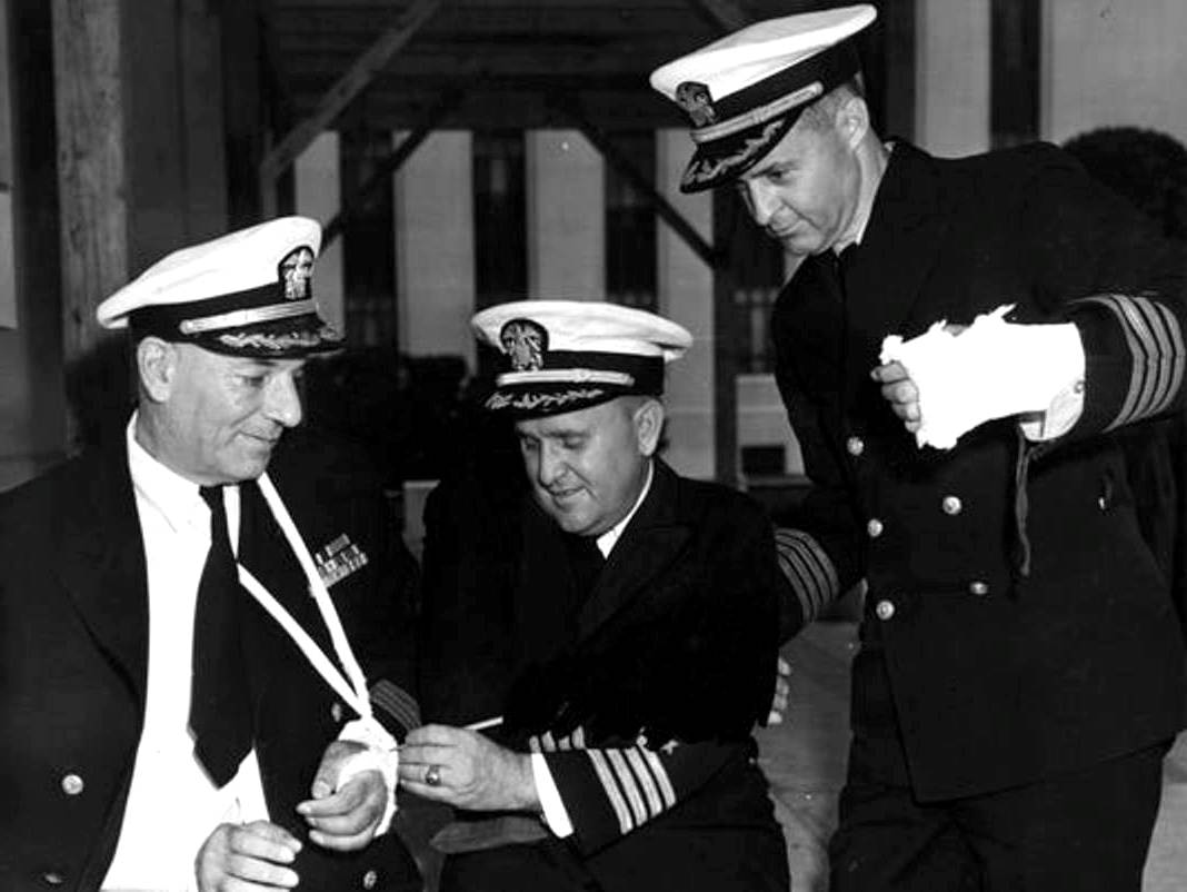 At the Naval Hospital at Bethesda Maryland, United States, Captain Dixie Kiefer (center) signs the cast of Captain George Mentz as Captain Thomas Inglis looks on, early 1945.