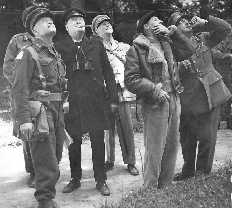 During Winston Churchill’s tour of the Normandy front, he and high ranking officers pause to watch German dive-bombers being engaged by British fighters and anti-aircraft fire, 12 Jun 1944, Normandy, France.