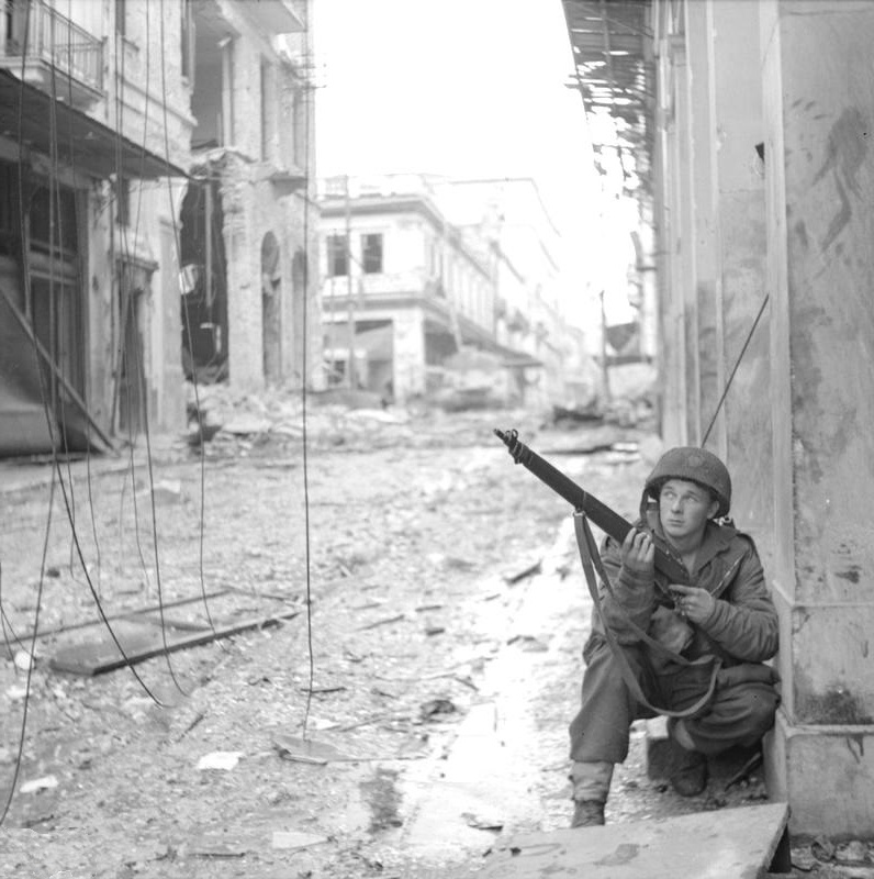 A British paratrooper with the 5th Scots Parachute Battalion takes cover in Athens, Greece during operations against ELAS (the Greek People's Liberation Army), 18 Dec 1944.
