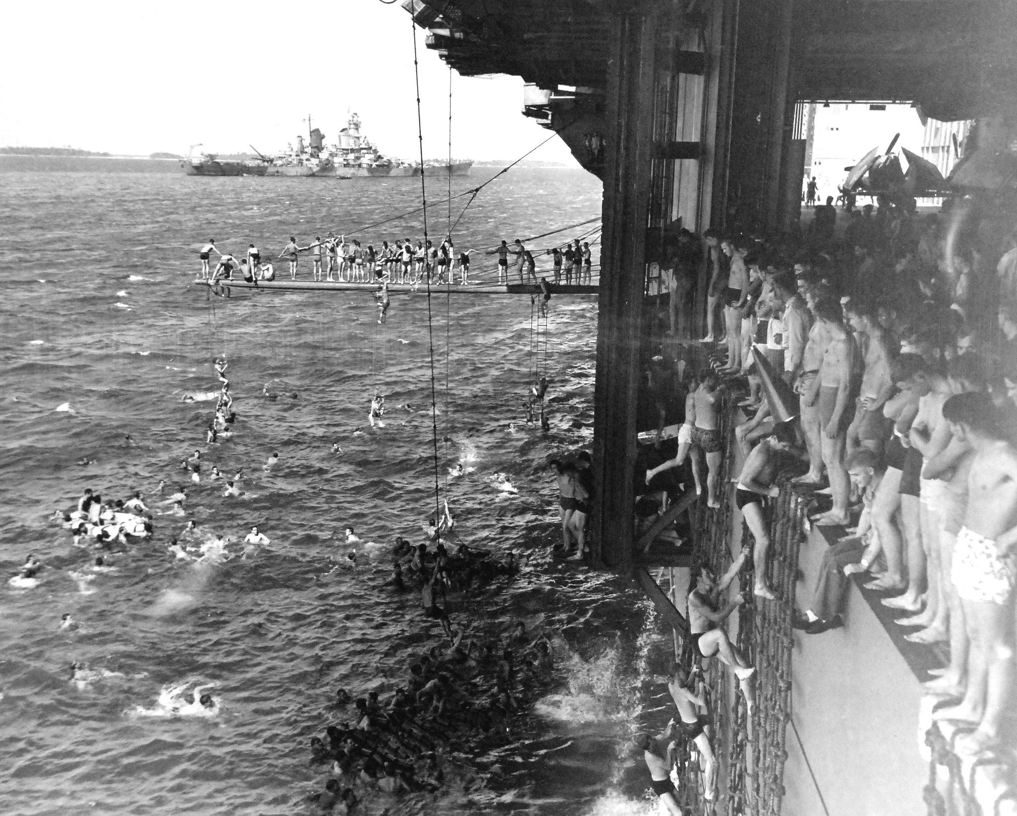 Members of the crew of the carrier USS Essex taking a swimming break in the Majuro Lagoon, Marshall Islands, Feb 1944. Note battleship USS Iowa in the background.